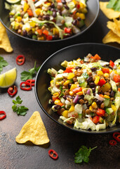 Mexican style salad of black beans, lentils, corn, tomato and lettuce with a salsa and tortilla chips