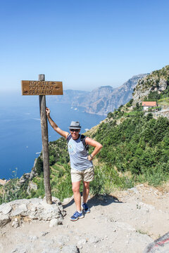 Caucasian hiker next to the signpost on the Sentiero degli dei trail ( path of the Gods) on the Amalfi coast, pointing towards Positano, Praiano and Nocelle. summer, Italy
