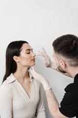 Obraz na płótnie Canvas ENT doctor is touching nose and consulting girl patient in medical clinic before septoplasty surgery. Rhinoplasty is reshaping nose surgery for change appearance of the nose and improve breathing.