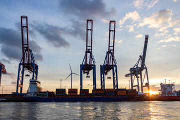 Obraz premium The busy harbour of Hamburg showing a skyline of cranes and container ships at sunset 
