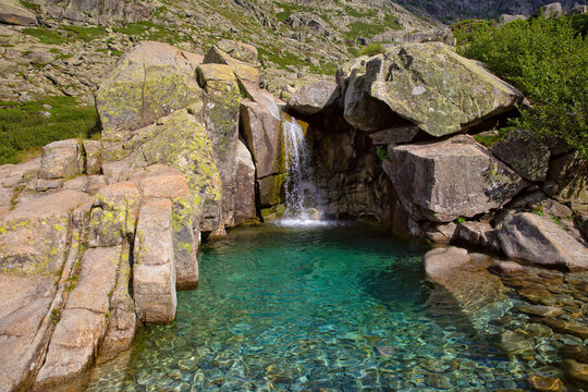 Waterfall in the mountains of the Restonica valley in central Corsica. Natural waterfall, rock and pool with emerald green watter in Restonica valley, Corsica island, France