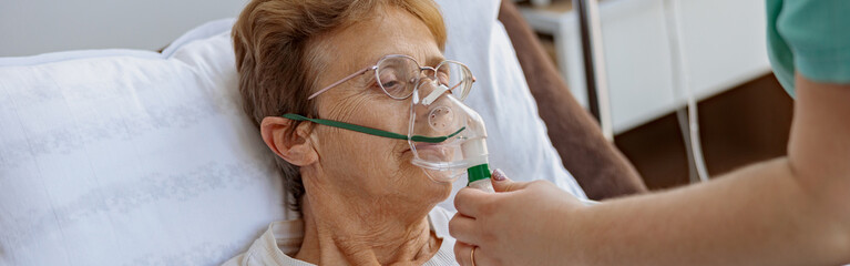 Nurse putting on a breathing mask on a female patient with covid-19. High quality photo