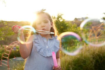 Niña hermosa latina al aire libre en el parque disfrutando jugando haciendo soplando burbujas...
