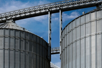 Fototapeta na wymiar Industrial facilities of feed and flour mills. Close-up of steel grain storage silos with conical bottom, can be used for various purposes.