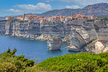Bonifacio at the edge of the chalk cliffs. Bonifacio is situated on the cliffs of a limestone peninsula sculpted and eroded by the sea, with buildings overhanging the edge, Corsica island, France