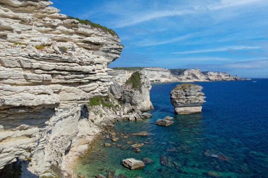 Scenic view of coastal limestone cliffs and the crystal clear sea at Bonifacio. The famous rugged chalk cliffs and turquoise blue sea coast at Bonifacio, Corsica island, France