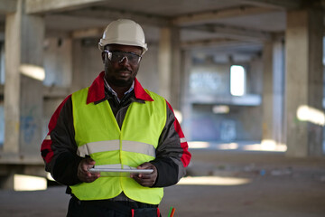 African american worker holds in hands tablet computer and looks at camera