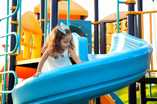 Ni&ntilde;a hermosa latina disfrutando y jugando en los juegos de un parque en el resbaladero desliz&aacute;ndose en el tobog&aacute;n divertida en una bonita &aacute;rea de juegos en un hermoso d&iacute;a soleado al aire libre