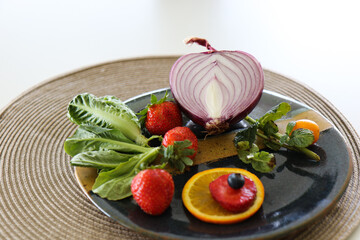 Plate with half red onion, lettuce and strawberries