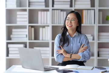 Beautiful and confident Asian businesswoman arms crossed thinking new idea at office.