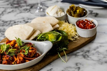 Closeup of tacos chicken tortillas and platter Mexican on a wooden board, blurred background
