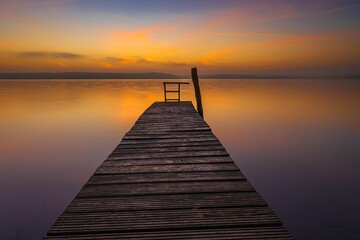 Fototapeta na wymiar Beautiful view of a sunset over the wooden dock in a Plauer See lake