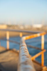 Selective focus of a rusty handrail in front of the sea during sunset