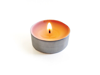 Isolated burning round candle. Front view of round tea light on white background. Burning flame in small round candle.