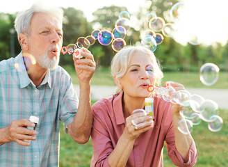 woman man senior couple  together elderly active happy retirement bubble soap blowing fun blow...