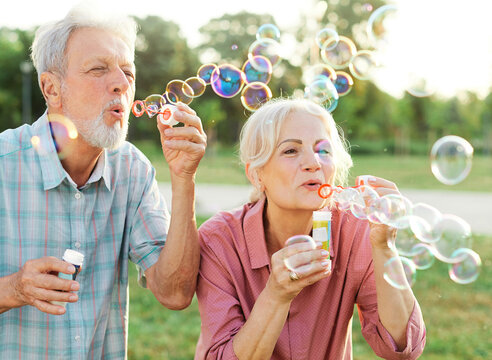 Woman Man Senior Couple  Together Elderly Active Happy Retirement Bubble Soap Blowing Fun Blow Vitality Bonding Park Outdoor Leisure Park Fun