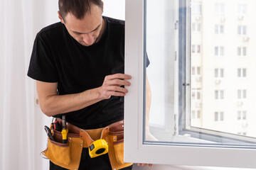 Handsome young man installing bay window in a new house construction site