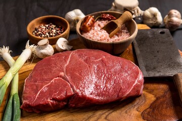 Raw rump beef cut or top sirloin meat steak on butcher table. Black background. Preparation of...