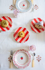overhead shot of beautiful french pastries on red and pink striped dessert plates on set table with embroidered tablecloth