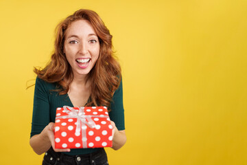 Redheaded woman smiling at camera with a gift