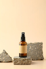 Amber glass spray bottle with blank label mockup on stone podium.