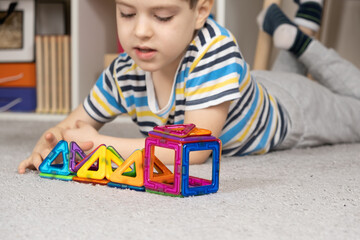 A cute 5 year old boy creates figures with a magnetic construction kit. The development of...