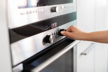 Unrecognizable Woman Using Electic Oven In Kitchen, Adjusting Temperature With Hand