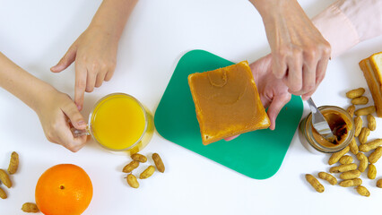 Mother preparing her son sandwitch with peanut butter on the kitchen