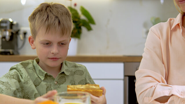 Boy drinking orange juice and eating sandwitch with peanut butter 