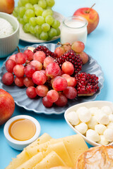 Jewish Shavuot Holiday Card. Dairy Products, Grapes, Cheese, Bread, Milk on Blue Background.