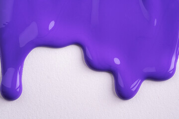 Violet liquid drops of paint color flow down on white canvas. Abstract art. Lilac paint dripping on...