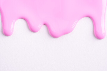 Pink liquid drops of paint color flow down on white canvas. Abstract art. Light pink paint dripping...