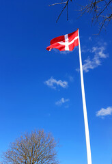 Red and white Danish flag in the blue sky on a sunny celebrations day in Denmark