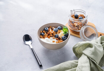 Muesli with vegetarian yogurt, banana and blueberries in a bowl on a light background. Healthy and dietary homemade granola for breakfast.