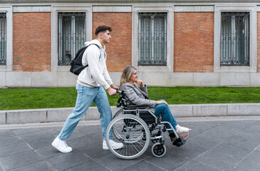 Teenager pushing her mother in a wheelchair down the street.