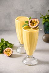 Indian two Passion Fruit Lassi on gray background. Vertical format. Traditional healthy drink with mango. Freshness lassi made of yogurt, water, spices, fruits and ice.