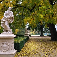Scenic view of marble sculptures in a park under green and yellow walnut tree
