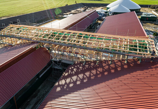 Luftbild-Nahaufnahme einer im Bau befindlichen Tierwohl - Schweinemastanlage,Holzkonstruktion für den zentralen Zuluftkanal auf dem neu eingedeckten Dachflächen.
