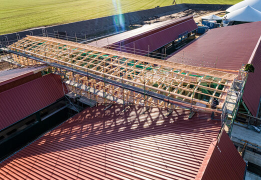 Luftbild-Nahaufnahme einer im Bau befindlichen Tierwohl - Schweinemastanlage,Holzkonstruktion für den zentralen Zuluftkanal auf dem neu eingedeckten Dachflächen.