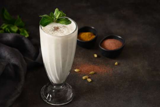 Indian Salty lassi with mint leaves and kala namak on black background. Traditional freshness lassi made of yogurt, water, spices and ice for hot climate. Close up. Copy space.