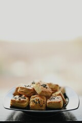 Vertical shot of homemade black sesame scones placed on a plate, against a bright background