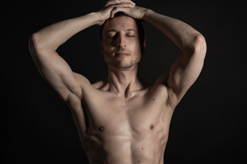 Adult attractive man with a beautiful body posing in the studio. Black background.	