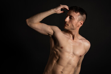 Obraz na płótnie Canvas Adult attractive man with a beautiful body posing in the studio. Black background. 