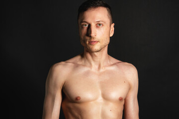Fototapeta na wymiar Adult attractive man with a beautiful body posing in the studio. Black background. 