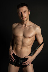 Fototapeta na wymiar Adult attractive man with a beautiful body posing in the studio. Black background. 