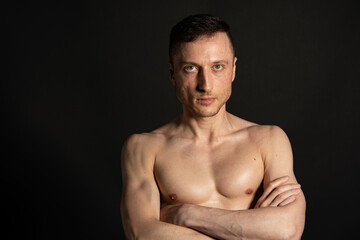 Naklejka premium Adult attractive man with a beautiful body posing in the studio. Black background. 