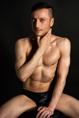 Fototapeta premium Adult attractive man with a beautiful body posing in the studio. Black background. 