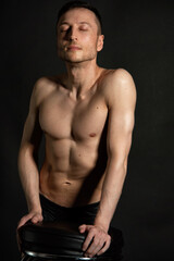 Fototapeta premium Adult attractive man with a beautiful body posing in the studio. Black background. 