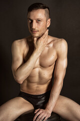 Fototapeta premium Adult attractive man with a beautiful body posing in the studio. Black background. 