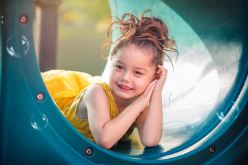 beautiful junior little girl playing in the park in yellow dress laughing with bubbles, screaming...